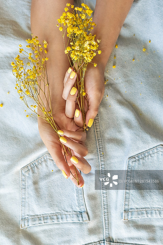 手持指甲油瓶的黄色美甲图片素材