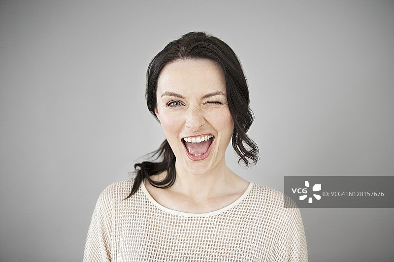 眨眼的快乐女人影棚照图片素材