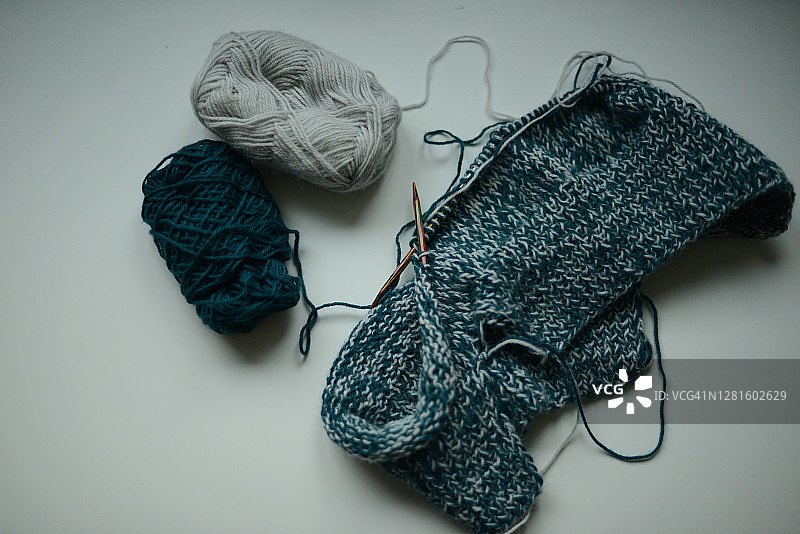 白色和蓝色羊毛纱线在环形针上编织毛衣，正在进行中图片素材