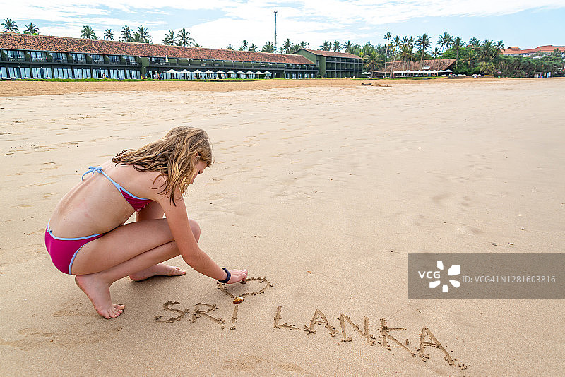 女孩在斯里兰卡本托塔海滩的沙滩上写字图片素材