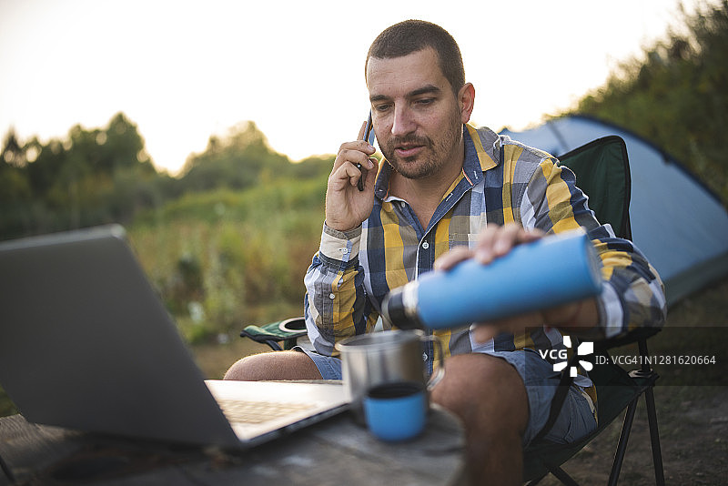 清晨，游客将热水从保温瓶中倒出。露营、旅行和运动概念图片素材