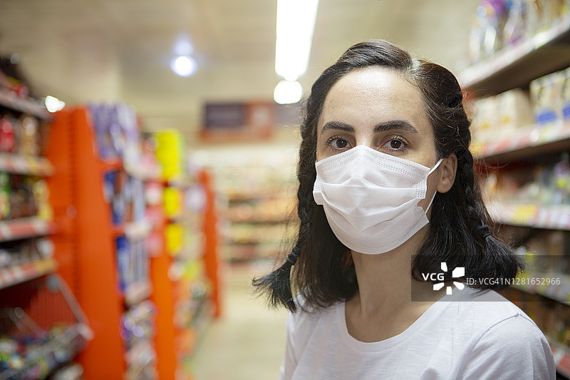 戴一次性医用口罩在超市购物的女人肖像图片素材