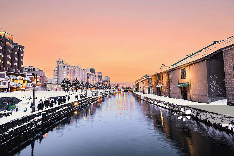 冬日雪中小樽运河的傍晚灯光与柔和的粉紫色云彩图片素材