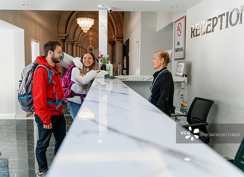 情侣戴着防护口罩在酒店前台办理入住图片素材
