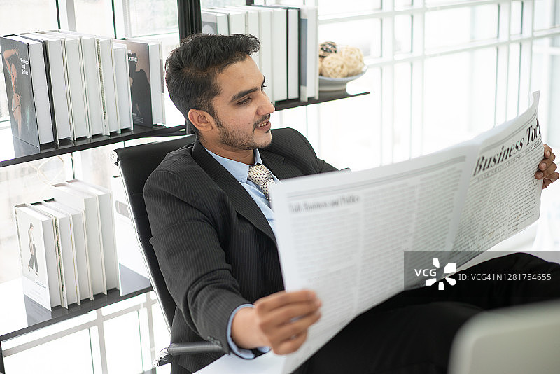 在桌旁看报纸的男人图片素材