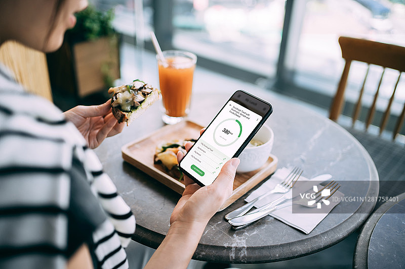 年轻亚裔女子在餐厅用手机查看健身饮食计划图片素材