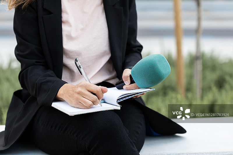 特写：新闻发布会上的女记者，做笔记，手持麦克风-库存照片图片素材