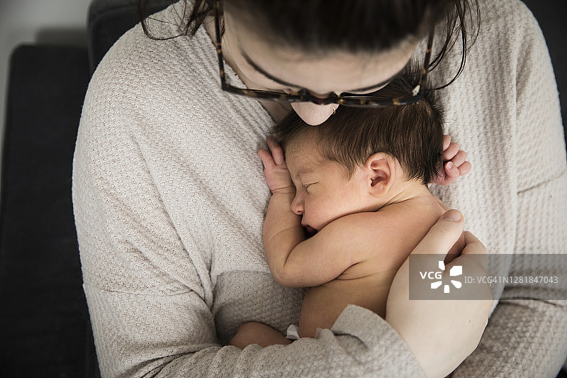 年轻母亲怀抱新生儿子的俯视特写图片素材