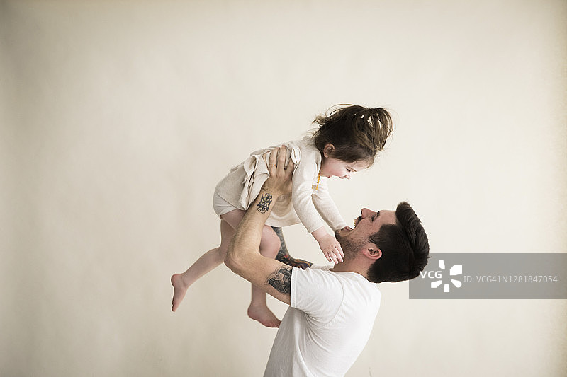 快乐的千禧潮人父亲高举幼儿图片素材