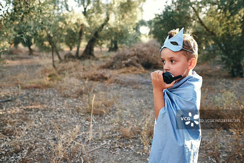 装扮成蓝色超级英雄的小孩拿着对讲机询问情况图片素材