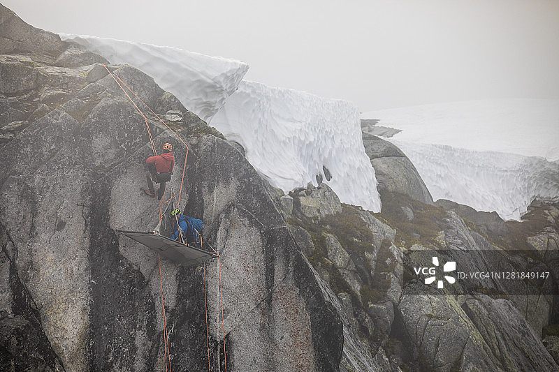 登山者使用绳索下降到岩壁上的露营平台上。图片素材