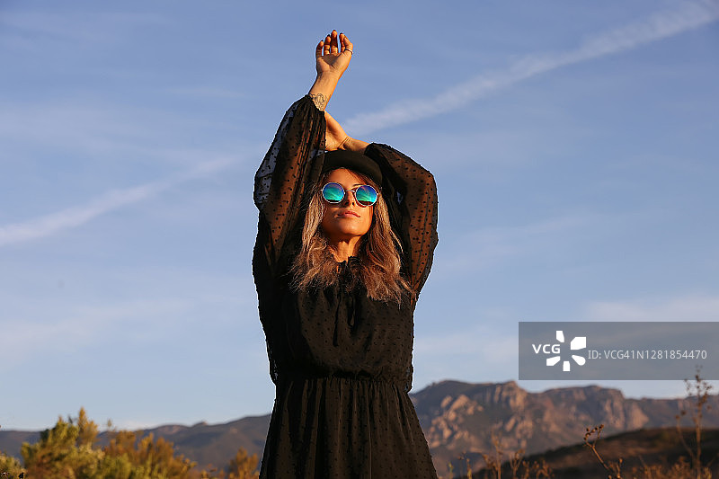 在田野里戴着帽子、身穿黑色连衣裙的女人图片素材