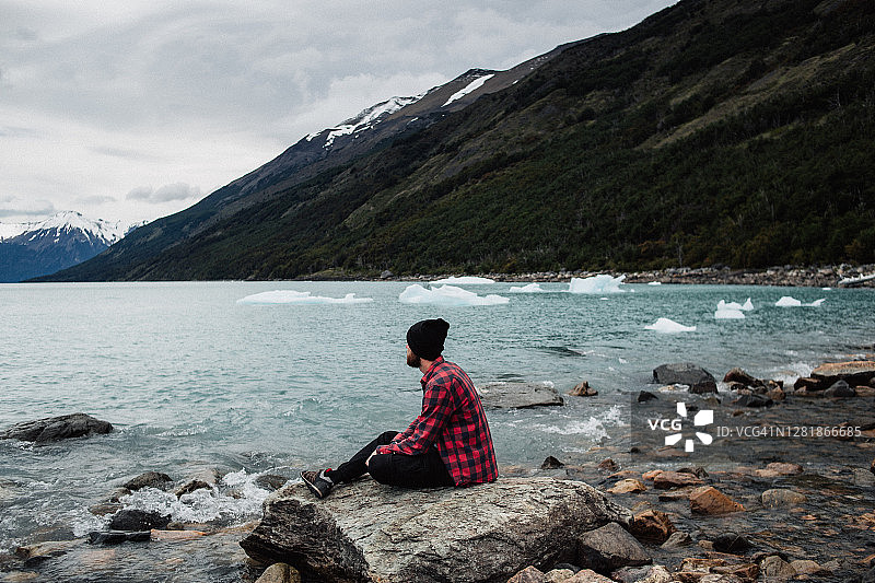 在巴塔哥尼亚水边欣赏风景的年轻白人男子图片素材