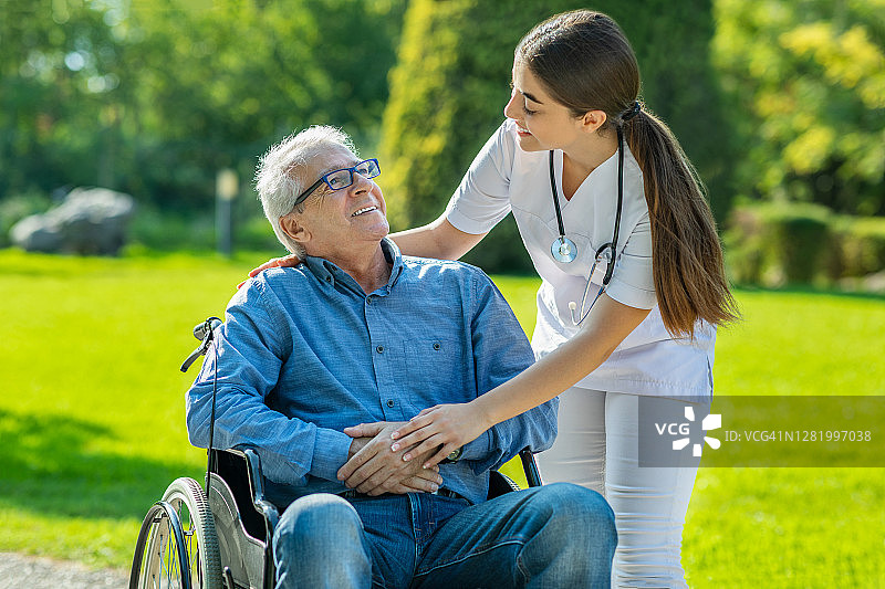 护士和老年病人在花园里坐轮椅图片素材