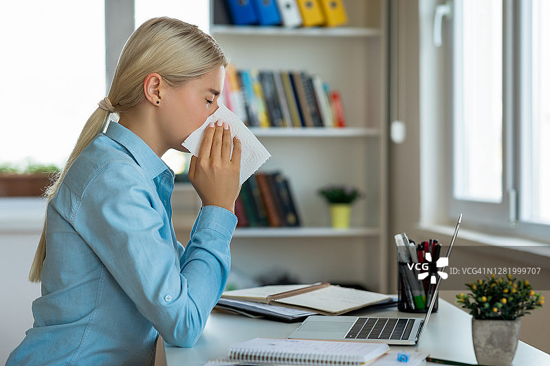 在家工作时擤鼻涕的年轻女子图片素材