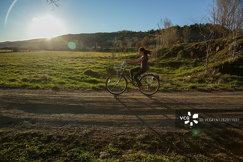 科罗拉多州帕奥尼亚日落时分在乡村土路上骑自行车的女孩图片素材