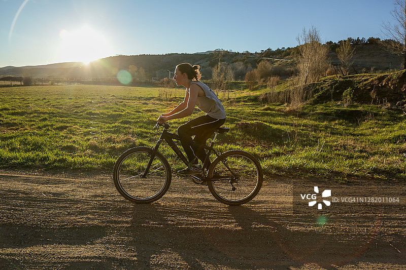 日落时分，科罗拉多州宝尼亚的乡村土路上，一个男孩骑着自行车图片素材