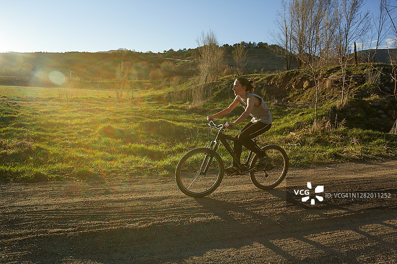 日落时分，科罗拉多州宝尼亚的乡村土路上，一个男孩骑着自行车图片素材