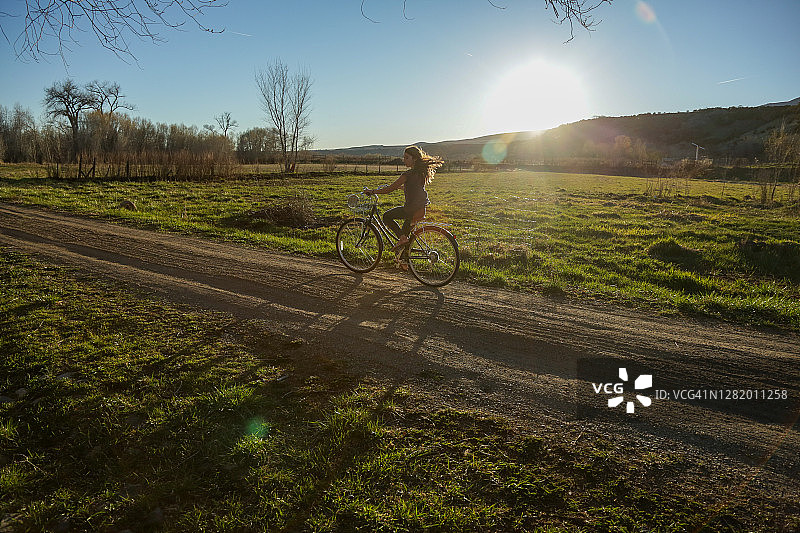 科罗拉多州帕奥尼亚日落时分在乡村土路上骑自行车的女孩图片素材