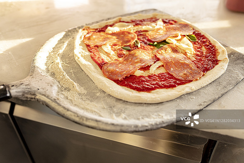 铲子上的萨拉米香肠披萨 - 准备放入披萨烤箱图片素材