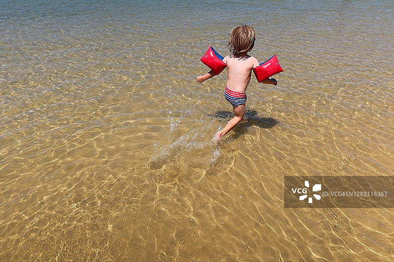 戴着臂章在水上奔跑的男孩图片素材