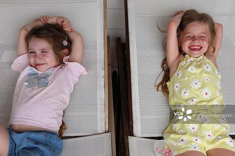 两个快乐的年轻女孩在躺椅上放松图片素材