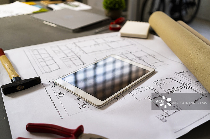 智能手机和锤子放置在建筑蓝图上图片素材