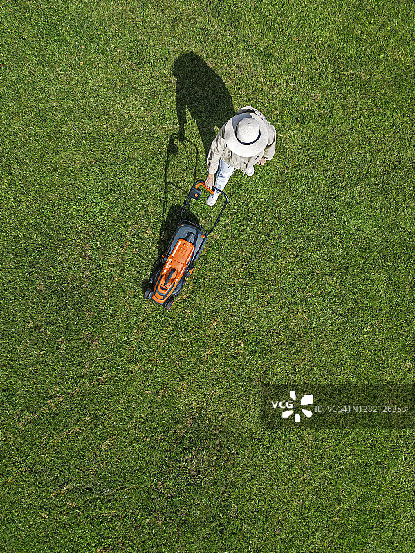 站在草地上使用割草机的女人图片素材
