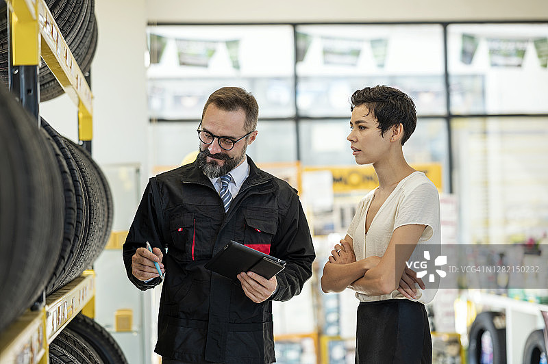 展厅客户服务：商店经理向女客户讲解汽车维修店的轮胎规格图片素材