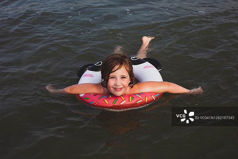 女孩戴着游泳圈在海里游泳图片素材