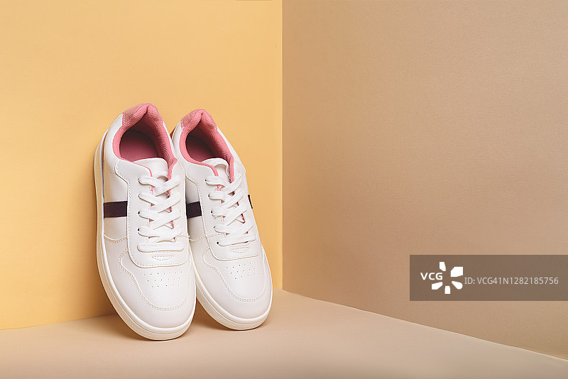 米色背景上的白色运动鞋图片素材