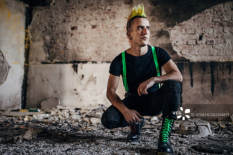 跪在废弃仓库里的年轻朋克图片素材