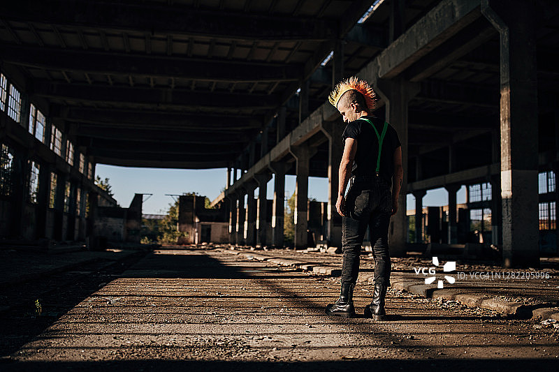 废弃仓库中，一位发型色彩鲜艳的朋克人士的背影图片素材