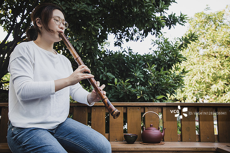 亚洲女性吹奏尺八，品味绿茶图片素材