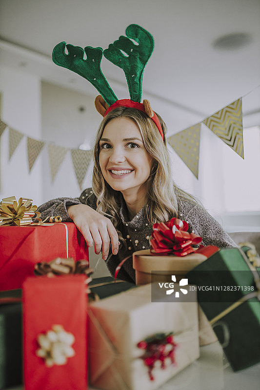 在舒适的家中带着圣诞礼物的微笑女性肖像图片素材