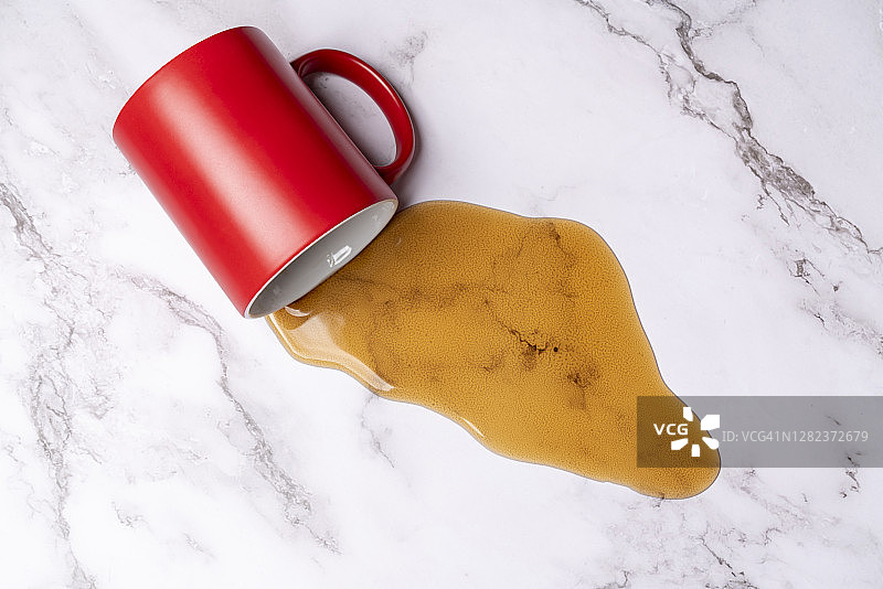 咖啡从咖啡杯中洒到大理石表面上图片素材