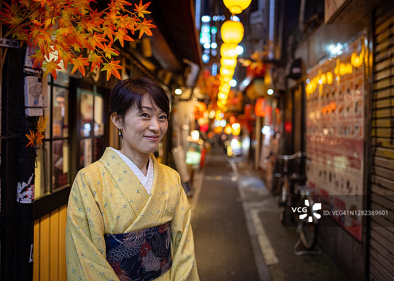 身穿和服的日本女人站在秋季的日式居酒屋巷子里图片素材