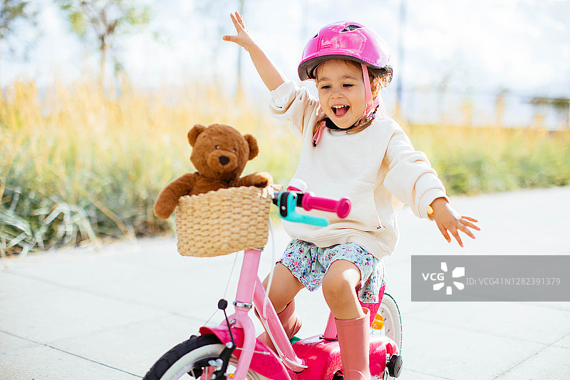 快乐的女孩在公园里骑自行车图片素材