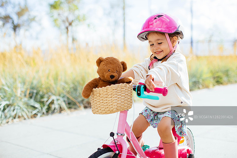 快乐的女孩在公园里骑自行车图片素材