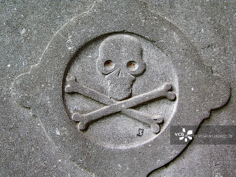 在废弃墓碑上雕刻着交叉骨的骷髅图片素材