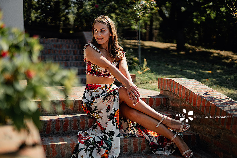 阳光明媚的日子里穿着优雅花卉图案连衣裙的女人图片素材