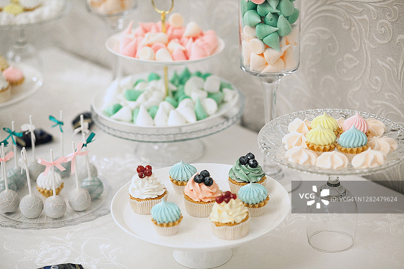 婚礼餐桌上装饰有新鲜浆果的彩色香草巧克力蛋白酥皮奶油纸杯蛋糕图片素材