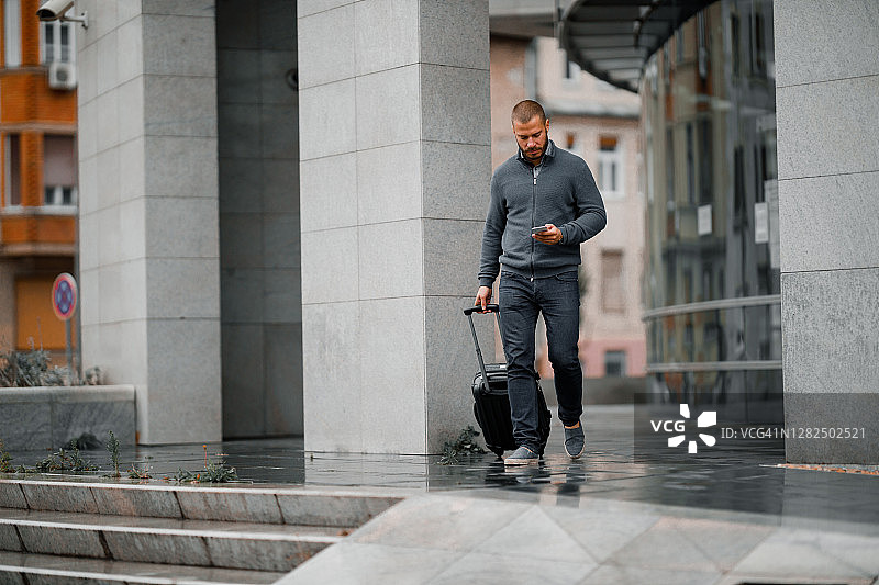 男人用手机拉着行李箱图片素材