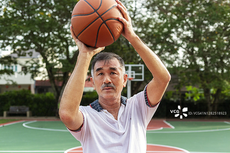 老年篮球运动员在篮筐投篮的正面照图片素材