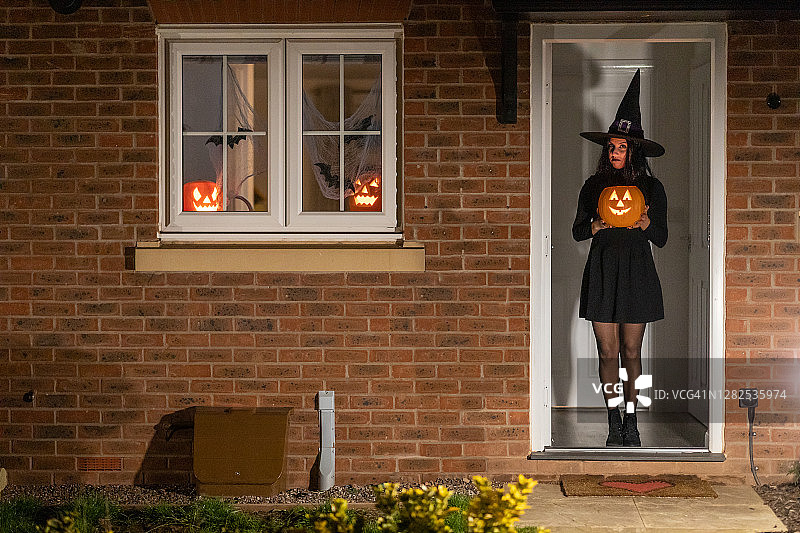 万圣节之夜，门口拿着南瓜的女巫图片素材