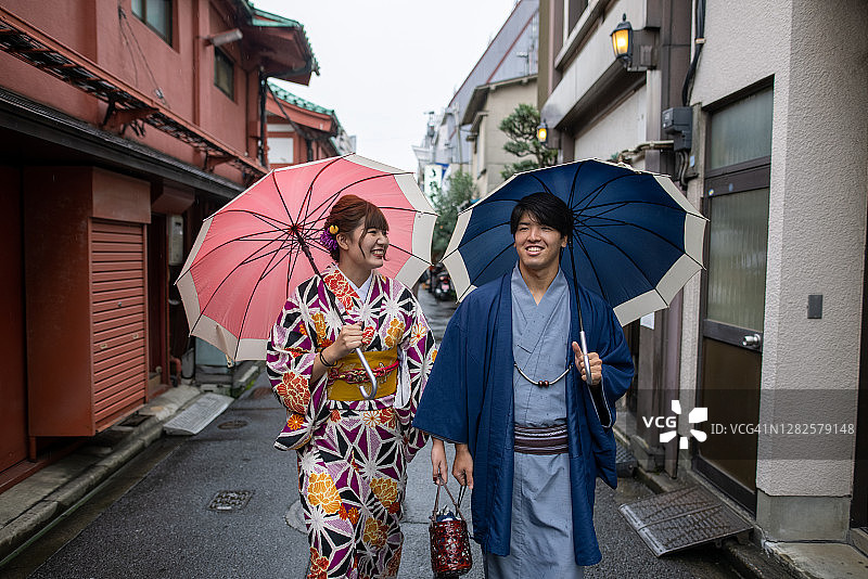 年轻情侣穿和服在雨天漫步于日本传统街道图片素材