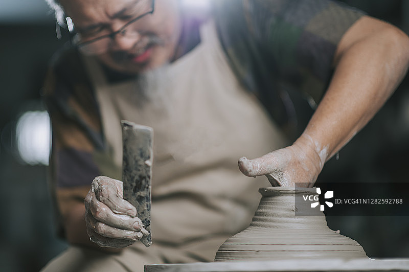 中国老年男性陶艺家在他的工作室里使用陶轮图片素材