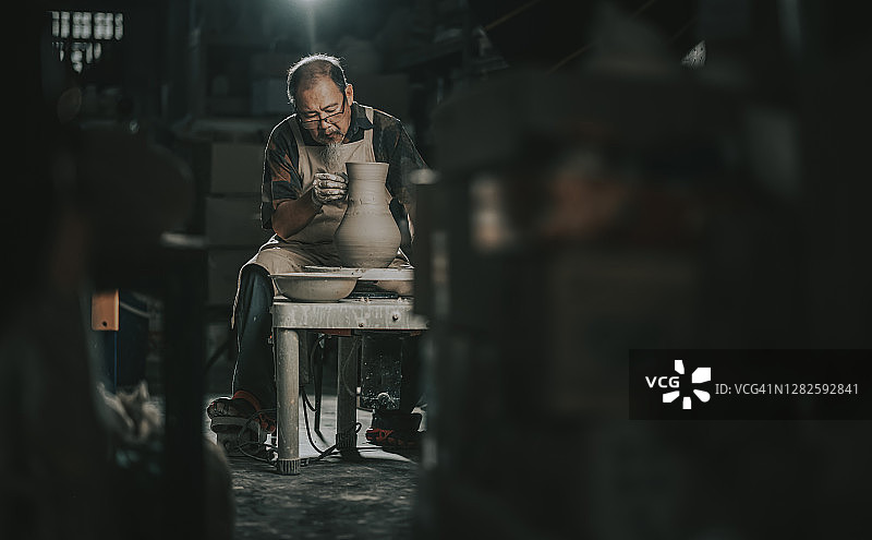 中国老年男性陶艺家在他的工作室里使用陶轮图片素材