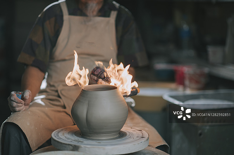 正在工作室用喷枪制作工艺品的亚洲老年陶艺家图片素材