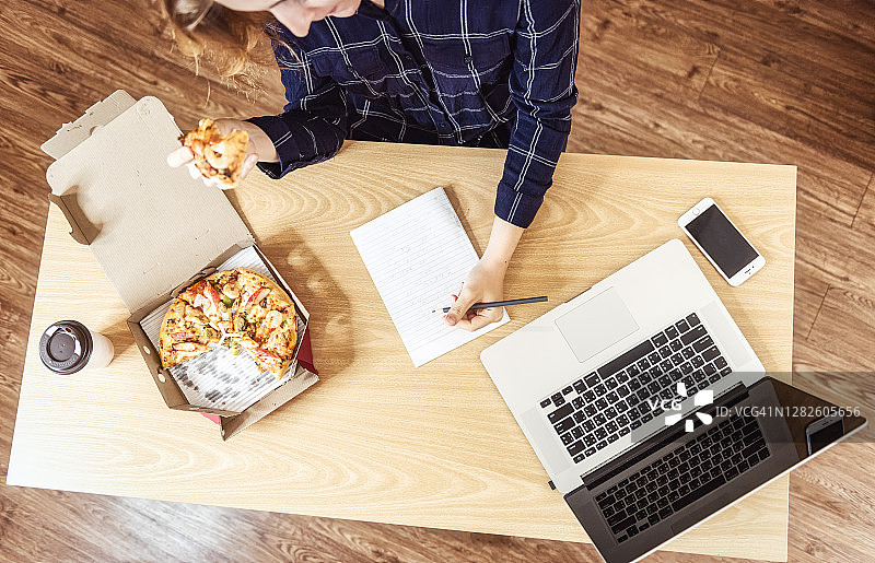 忙碌的工作：女士在家中办公室享用商务午餐图片素材